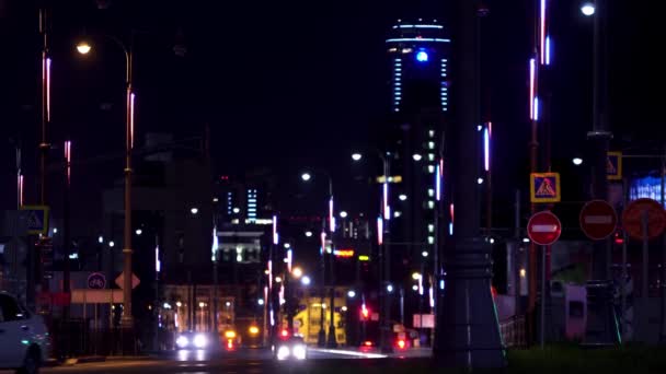 Paisaje nocturno del gran centro de la ciudad con luces brillantes y coches raros en movimiento. Imágenes de archivo. Carretera del distrito central de la ciudad iluminada por farolas . — Vídeo de stock