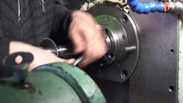 Mechanik naprawczy w fabryce dostosowuje maszynę z dużym i ciężkim kluczem, trzymając ją obiema rękami. Materiał filmowy. Zbliżenie maszyn i sprzętu profesjonalnego. — Wideo stockowe
