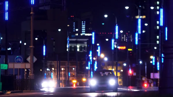 Nattlandskap i den stora stadskärnan med lysande ljus och flytta sällsynta bilar. Lagerbilder. Vägen i den centrala stadsdelen upplyst av gatlyktor. — Stockfoto