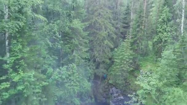Beautiful misty morning view of foggy gorge in dense green summer forest and a man in bright clothes standing at the edge. Stock footage. Aerial of mixed forest and steep rock slopes. — Stock Video
