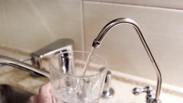 Woda wlewana do szklanki z kranu kuchennego. Koncepcja. Zbliżenie wody z kranu wlewanej do szklanki w kuchni — Wideo stockowe