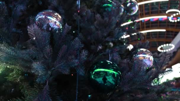 ショッピングセンターでクリスマスツリーのクローズアップ。コンセプト。クリスマスと新年の休日のためのライトで飾られた緑のクリスマスツリーの枝の閉鎖 — ストック動画