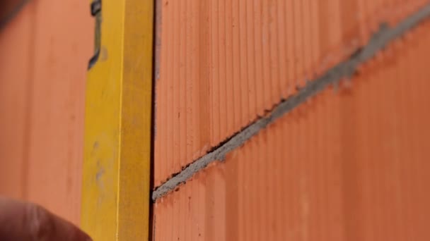 Bricklayer usando um nível de espírito para verificar a parede e desenhar uma linha com um lápis. Imagens de stock. Close-up de mãos de homem em luvas de proteção que trabalham com ferramenta profissional . — Vídeo de Stock