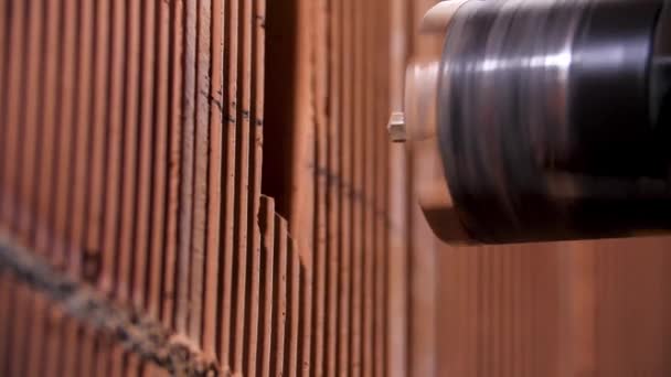 Primer plano de macho con perforador eléctrico antes de hacer un agujero en la pared de ladrillo rojo. Imágenes de archivo. Herramienta de trabajo y profesional en el sitio de construcción . — Vídeo de stock