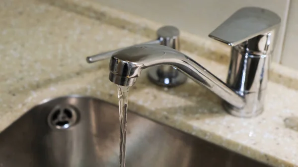 Pouring water from a tap in a kitchen. Concept. Close-up of water pouring from the tap — 스톡 사진