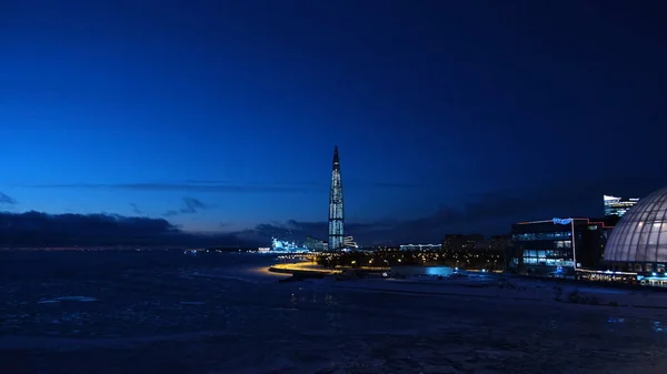 Uitzicht op een wolkenkrabber bedekt met lantaarns in een moderne stad 's nachts. Concept. Winterlandschap van een moderne wolkenkrabber 's nachts — Stockfoto