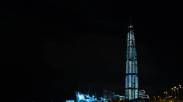 Vista de un rascacielos cubierto de linternas en una ciudad moderna por la noche. Concepto. Paisaje urbano invernal de un rascacielos moderno por la noche —  Fotos de Stock
