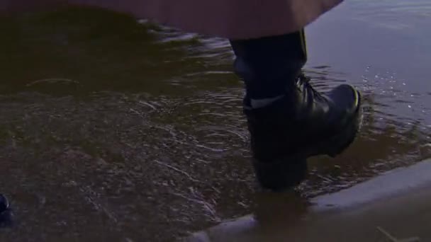 Primer plano de la mujer caminando sobre el agua en zapatos. Imágenes de archivo. Mujer en negro zapatos de cuero con estilo camina sobre el agua caminando en la playa por la noche — Vídeos de Stock