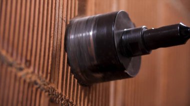 Elmas uçlu matkap ucu tutan bir adamın elektrik prizinin montajı için hazırlık çalışması. Stok görüntüleri. Kırmızı tuğla duvarın içinde yuvarlak delik.