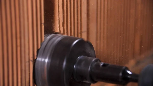 Primer plano del proceso de perforación en la pared para toma de corriente eléctrica por herramienta de taladros de martillo eléctrico. Imágenes de archivo. Hacer un agujero dentro de la pared de ladrillo rojo con un equipo profesional . — Foto de Stock