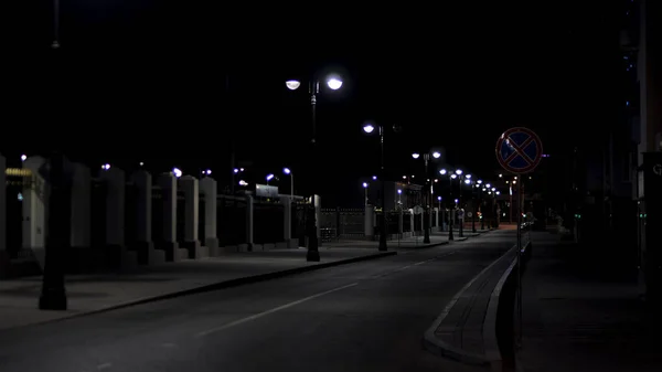 Gyönyörű és nyugodt atmoszférája a nyári éjszakának a nagyvárosban, sötét utcában, sok ragyogó lámpással. Készletfelvétel. Üres út és járda. — Stock Fotó