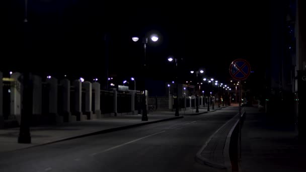 Beautiful and calm atmosphere of the summer night in big city, dark street with many shining lanterns. Stock footage. Empty road and sidewalk. — ストック動画