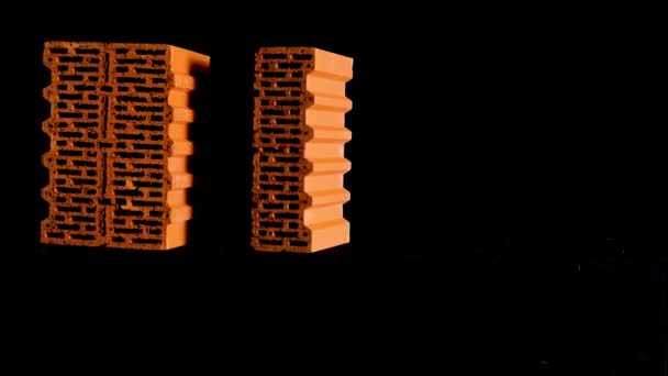 New red bricks isolated on black background, concept of materials at the construction site. Stock footage. Two perforated bricks moving against black screen. — 비디오