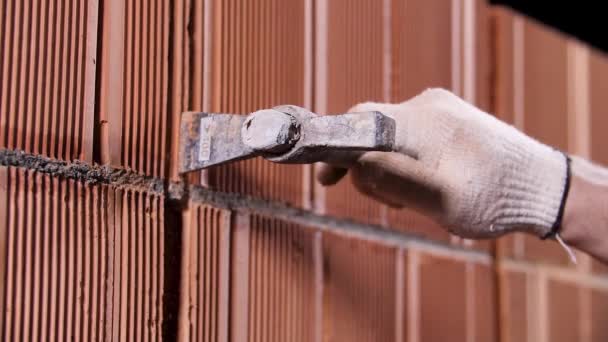 Sluiten van een arbeider met metalen hamer en maken van een gat in de rode keramische blok muur. Voorraadbeelden. Stadium van nieuwbouw. — Stockvideo