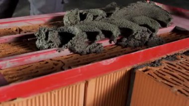 Tuğla duvarda bir tabaka yapmak için ahşap çerçeveye havan topu koyan bir işçiye yaklaş. Stok görüntüleri. İnşaat alanında çimento düzeyi.