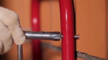 Kırmızı tuğla duvara metal tüp takmak için soket anahtarı kullanan bir erkek işçinin ellerini kapatın. Stok görüntüleri. Ev inşa süreci.
