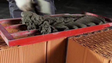 Tuğla duvarda bir tabaka yapmak için ahşap çerçeveye havan topu koyan bir işçiye yaklaş. Stok görüntüleri. İnşaat alanında çimento düzeyi.