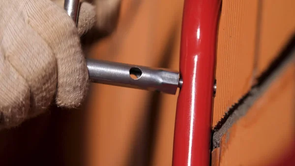 Close up de um trabalhador do sexo masculino mãos usando chave de encaixe para anexar tubo de metal para a parede de tijolo vermelho. Imagens de stock. O processo de construção de casas . — Fotografia de Stock