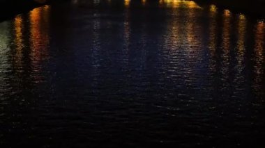 Gece şehrin ışıklarını yansıtan güzel, pırıl pırıl su. Kavram. Kanal suyunun koyu dalgaları geceleri bulanık ışıkları yansıtır.