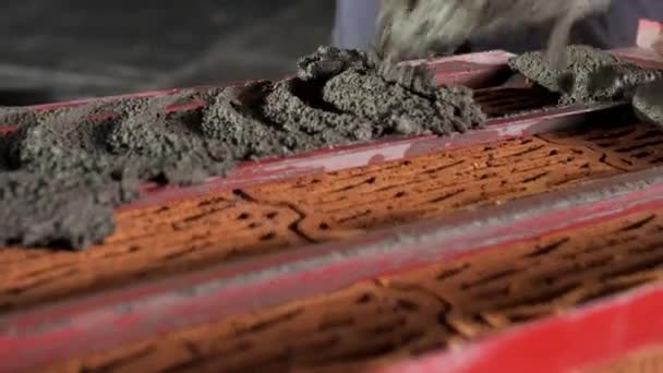 Metselaar zet nog een rij cement neer met behulp van een speciale rode vorm. Voorraadbeelden. Sluiten van het bouwproces op de bouwplaats. — Stockvideo