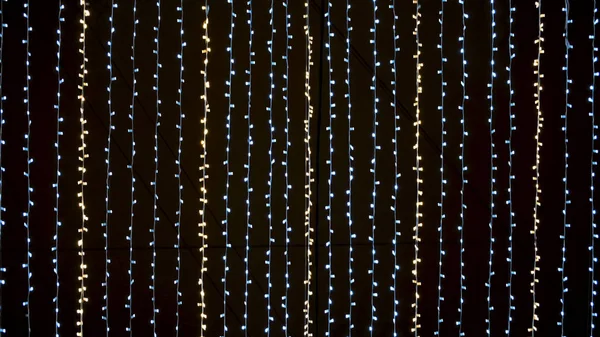 Dolní pohled na mnoho malých žárovek, slavnostní věnce osvětlující noční oblohu. Koncept. Multicolored street garland stretched against the black night sky. — Stock fotografie