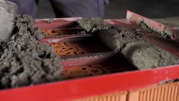 Bricklayer putting down raw cement and making an even layer to put another brick on it. Stock footage. Close up of making a brick wall process. — Stock Video