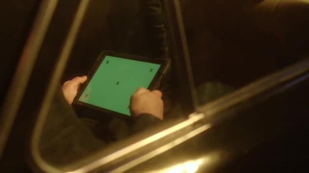 Atomobili olan ve tablette oturan bir adamın yakın çekimi. Stok görüntüleri. Adam karanlık tünelden arabayla geçiyor ve yeşil ekranlı tablet üzerinde çalışırken çalışıyor. — Stok video