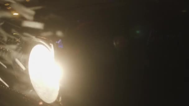 Close-up of headlight of old car at night. Stock footage. Round retro car headlight shines during ride on snowy night. Glowing headlight illuminates falling snow on night trip — Stock Video