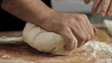 Profesyonel Baker hamur yoğurma makinesine yakın çekim. Stok görüntüleri. Fırın şefinin dev elleri ahşap tahtada un ile hamur yoğurur.