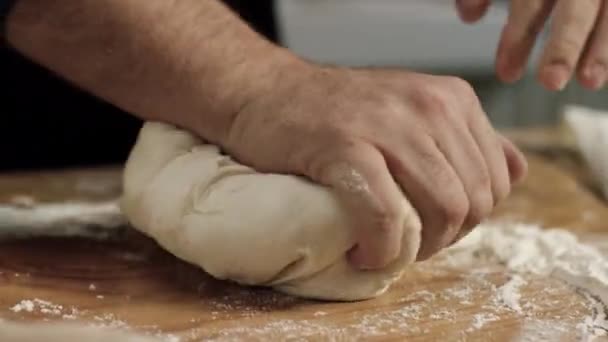 Primer plano de Baker amasando masa profesional. Imágenes de archivo. Las manos gigantes del chef de panadería amasan masa con harina sobre tabla de madera — Vídeo de stock