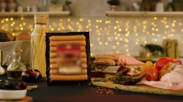 Bord med kött snacks på bakgrund av garland. Lagerbilder. Närbild av ingredienser för festligt bord i kök med krans på bakgrunden — Stockvideo