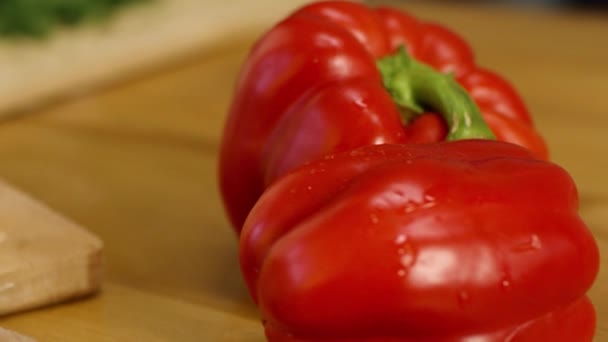 Close-up of two red ripe sweet peppers. Stock footage. Beautiful juicy sweet peppers lie before slicing on wooden background. Juicy ripe vegetables — Stock Video