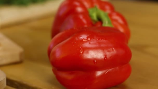 Close-up de dois pimentos vermelhos maduros. Imagens de stock. Belos pimentos doces suculentos jazem antes de fatiar no fundo de madeira. Legumes maduros suculentos — Vídeo de Stock