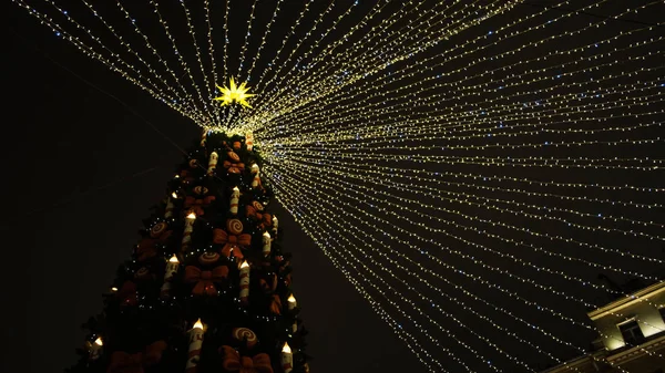 Krásné město vánoční strom s girlandy na pozadí tmavé noční obloze. Koncept. Krásný jasný vánoční stromek s girlandami na oblačný zimní den — Stock fotografie