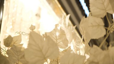 Beyaz yapay yaprakların yakın çekimi. Kavram. Dekorasyon için kumaştan yapılmış yapay beyaz yapraklar. Dekoratif beyaz yapraklar geceleri rüzgarda hışırdıyor
