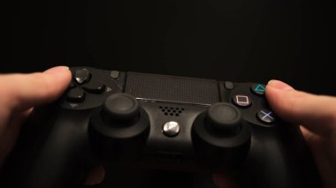 joystick tuşlarına basan bir kadının yakın çekimi. Kavram. Kadın elleri joystick 'i tutuyor ve siyah arka plandaki tuşlara basıyor. Konsoldaki meşgul oyun sırasında joystick 'teki düğmelere hızlıca bas