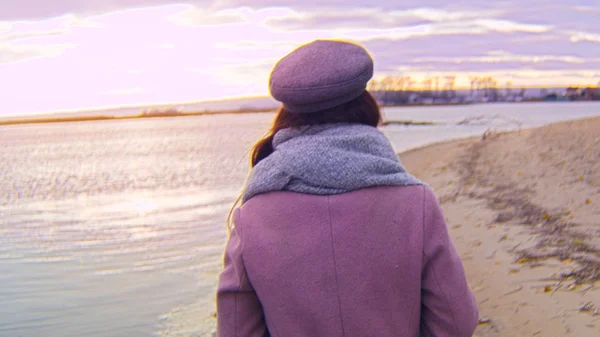 海岸の夕日の風景を背景に歩いて魅力的な女性のリアビュー。ストック映像だ秋の砂浜を歩く夕日と若い女性の色の美しい海岸風景 — ストック写真
