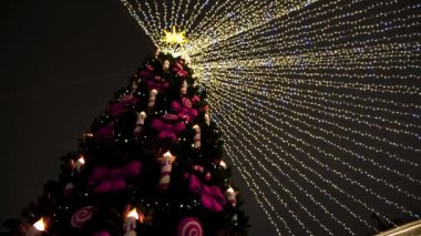 Noel ağacı ışıkları ve gece gökyüzü arka planında süslemeler. Kavram. Mumlar ve kurdelelerle ladin ağacının alt manzarası.