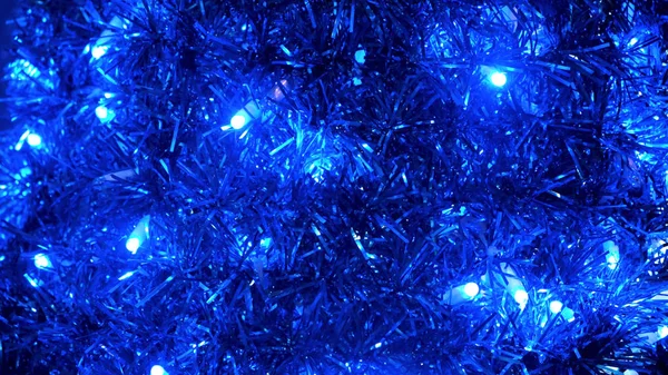 Fondo festivo de Navidad brillante de guirnalda y bombillas parpadeantes. Concepto. Primer plano de año nuevo oropel azul, decoraciones para el hogar . —  Fotos de Stock