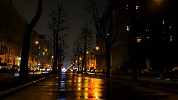 Hermosa noche en la gran ciudad y la calle bajo las luces de linternas amarillas. Concepto. callejón de la ciudad con coches en movimiento . — Foto de Stock
