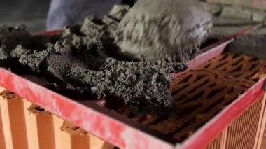 İnşaat işçisi tuğla sabitlemesi için çiğ havan topunu dengelemek için mala kullanıyor. Stok görüntüleri. Kırmızı tuğlalara çimento döşemeyi kapat.