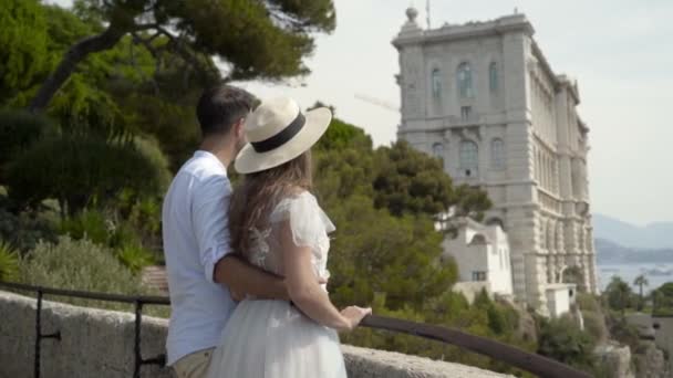 Casal jovem fica no deck de observação e olhar para a cidade europeia. Acção. Belo casal na Europa — Vídeo de Stock