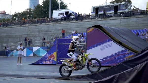 Ekaterimburgo, Rusia-agosto de 2019: Los motociclistas realizan acrobacias. Acción. Motociclistas profesionales realizan trucos desde trampolines sobre fondo de stands con gente y cielo azul — Foto de Stock