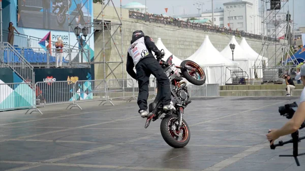 Jekatěrinburg, Rusko-srpen, 2019: Motorkář provádí kaskadérské výkony na pozadí lidí. Akce. Profesionální motocyklista provádí krásné kousky na pozadí stánků s lidmi na freestyle — Stock fotografie