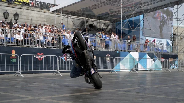 Yekaterinburg, Rusland-augustus 2019: Motorrijder voert stunts uit op achtergrond van mensen. Actie. Professionele motorrijder voert mooie stunts uit op de achtergrond van stands met mensen op freestyle — Stockfoto