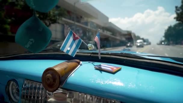 Close-up of flags of America and Cuba in car. Action. Beautiful flags adorn panel of retro car on background of road in hot country. Decoration for car — 비디오