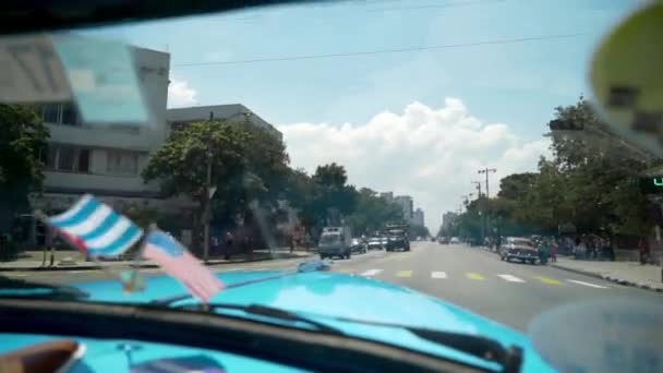 Close-up of flags of America and Cuba in car. Action. Beautiful flags adorn panel of retro car on background of road in hot country. Decoration for car — 비디오