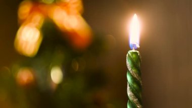 Bulanık renkli bir Noel geçmişinde yanan mum. Kavram. Yeşil Yeni Yıl mumunun alevi sönmüş çam ağacının önüne konur..