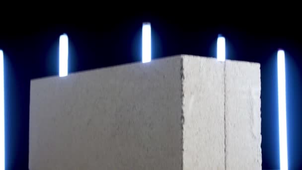 Demostración de bloque de hormigón blanco sobre fondo negro con lámparas de neón azul veral. Imágenes de archivo. Primer plano de losa de hormigón, concepto de materiales de construcción . — Vídeos de Stock