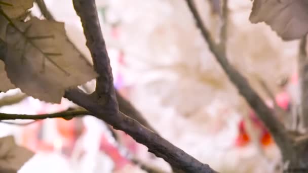 Primer plano de hojas blancas de un árbol artificial balanceándose en el viento bajo la luz brillante de una linterna. Concepto. Hermosas hojas falsas tiernas sobre fondo borroso . — Vídeo de stock